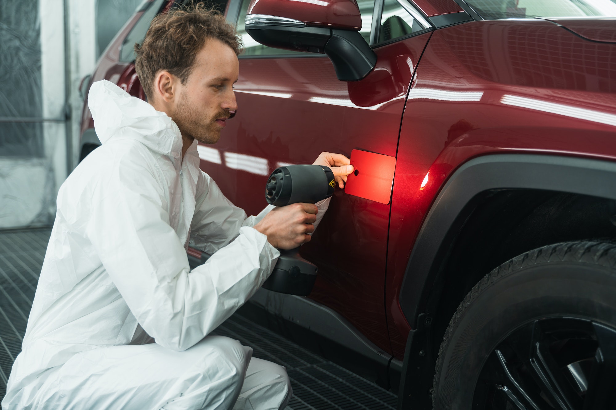 Professional auto painter matches car paint color with lamp and samples